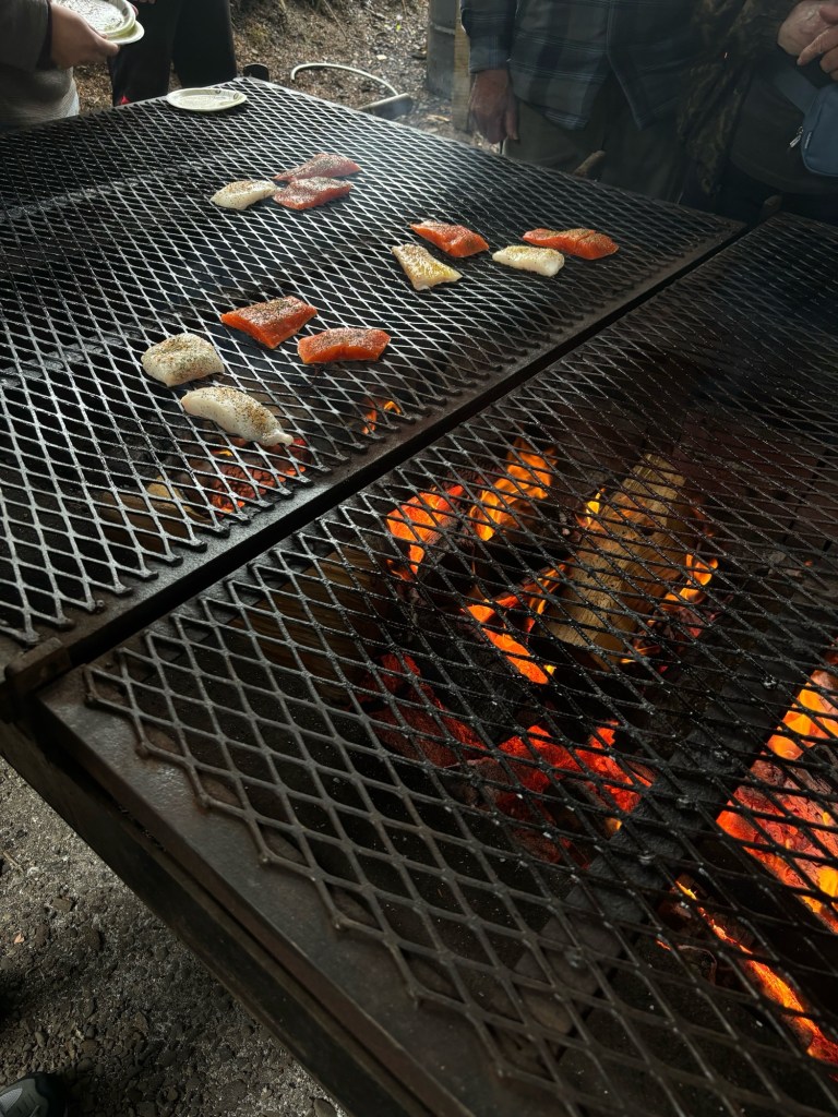 Grilling halibut and salmon over wood fire during In Alaska's Wildest Kitchen cruise excursion at Icy Strait Point, Hoonah, Alaska